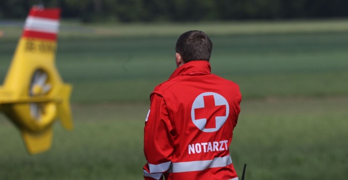Einen Notarzt, im Hintergrund ein Hubschrauber.