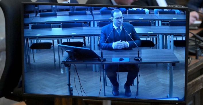 Aufnahme eines Monitors, auf dem Florian Teichtmeister während seiner Gerichstverhandlung zu sehen ist.
