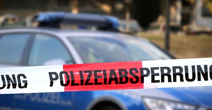 Themenbild: Polizeiabsperrung mit Polizeiauto im Hintergrund
