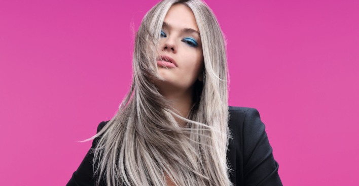 Blondes Model vor einer pinken Wand bei einem Fotoshootings