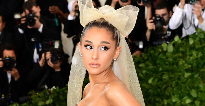 Ariana Grande mit einer gelben Schleife auf dem Kopf am roten Teppich.