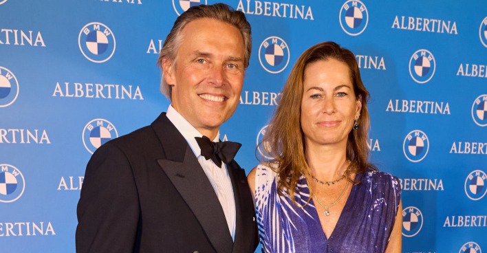 Birgit Lauda mit Partner Marcus Sieberer vor einer blauen Fotowand