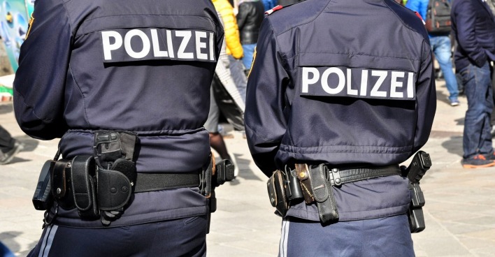 Zwei Polizisten von hinten, auf ihrem Rücken die Aufschrift "Polizei".