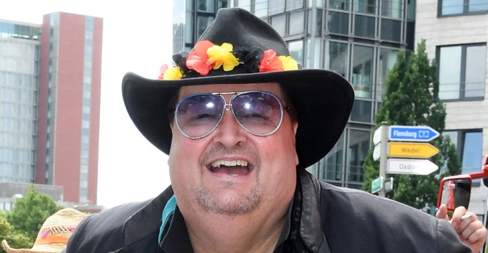 Andreas Ellermann mit einem schwarzen Hut und Blumendekoration in den Farben der Deutschland Flagge.