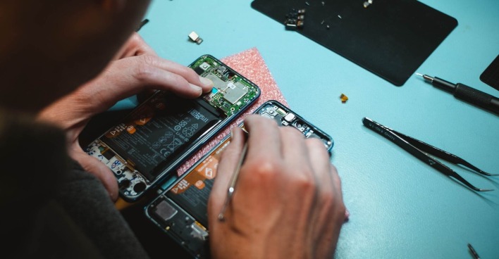 Ein Mann repariert ein aufgeschraubtes Smartphone