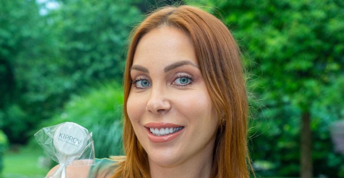 Tara Tabitha mit kupfer Haaren vor einem Park.