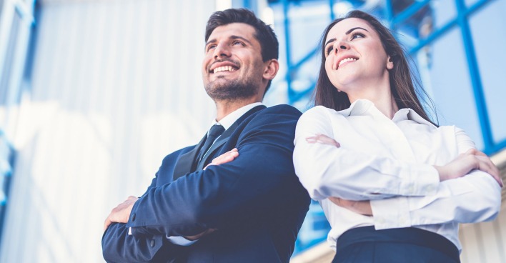 Junge erfolgreiche Frau und junger erfolgreicher Mann in blauer Businesskleidung | Credit: iStock.com/Viacheslav Peretiatko