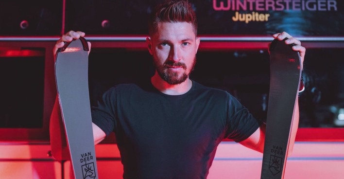 Marcel Hirscher in einem schwarzen T-Shirt, der zwei Prototypen seiner Van-Deer-Skier in die Kamera hält