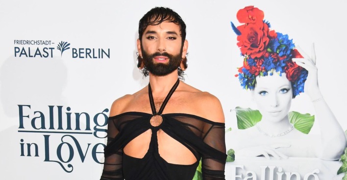 Conchita Wurst am Red Carpet mit einem freizügigen schwarzen Kleid und kurzen schwarzen Haaren.