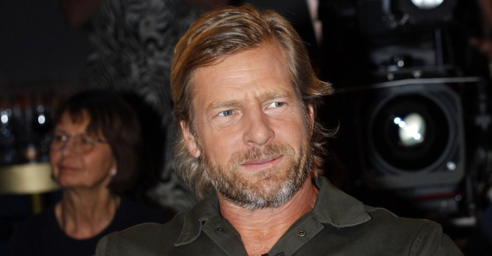 Schauspieler Henning Baum mit einem schwarzen Hemd und leicht gegolten blonden Haaren. Er trägt einen Dreitagebart.