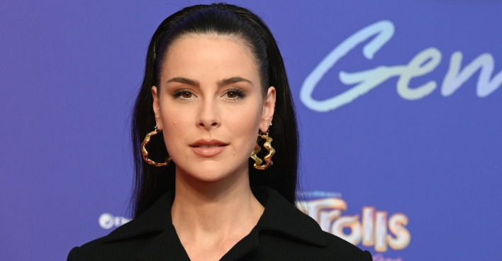 Lena Meyer Landrut mit offenen Haaren, einem Haarreifen, großen Ohrringen und einem schwarzen Sakko.