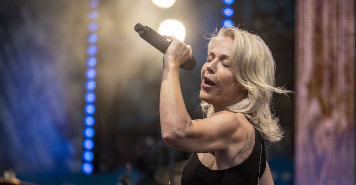 Schlagerstar Michelle mit offenen blonden Haaren, einem Mikrofon singend auf der Bühne.