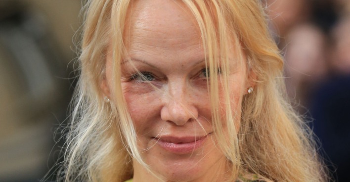 Pamela Anderson mit blonden Haaren die ihr ins Gesicht wehen.