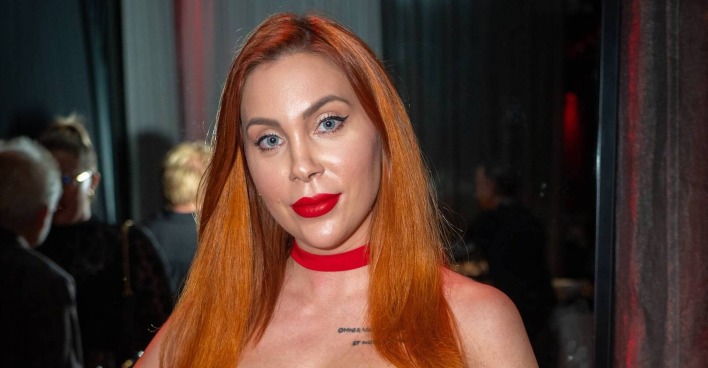 Tara Tabitha mit einem roten Lippenstift und langen kupfer Haaren.