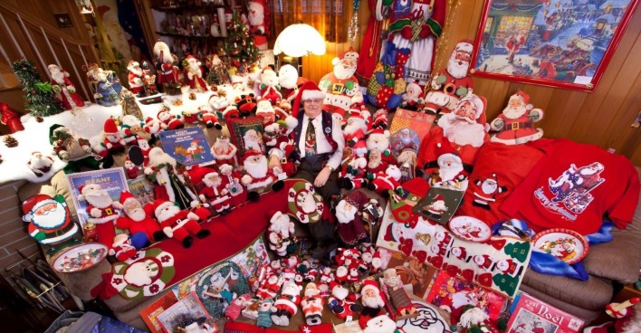 Mann sitzt mitten in seiner Weihnachtsmann-Artikel Sammlung