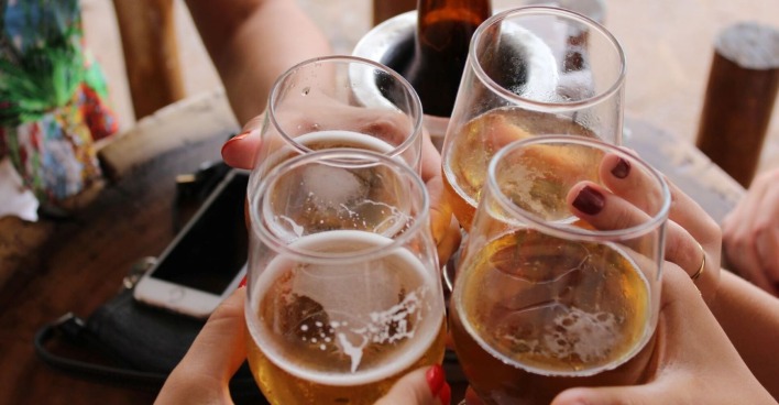 Vier Mencshen stoßen mit Bier an