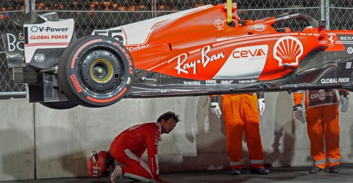Der desolate Wagen von Ferrari wird von der Strecke gehoben. Mechaniker inspizieren den Unterboden.