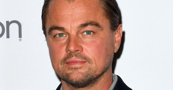 Leonardo DiCaprio steht vor einer weißen Fotoleinwand.