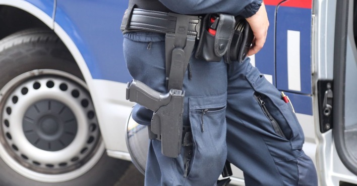 Polizeibeamter vor einem Polizeiauto.