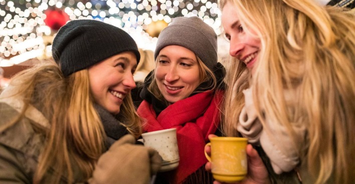 Drei Mädels trinken einen Glühwein am Christkindlmarkt.