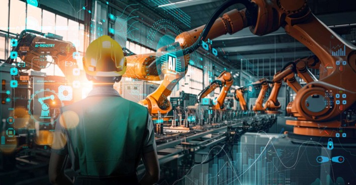 Ein Mann in einer Fabrik mit vielen Robotergreifarmen.