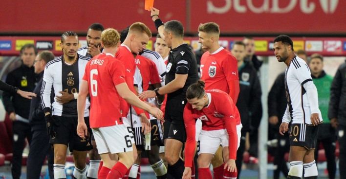 Gemenge deutscher und östererichischer Spieler, ein Österreich liegt am Boden. Der Schiedsrichter zeigt die rote Karte.