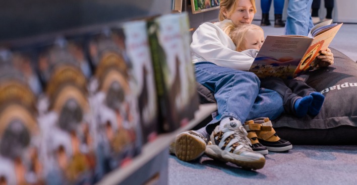 Eine Mutter und ihr kleines Kind haben es sich auf der Buch Wien 23 in einem Sitzsack gemütlich gemacht und schmökern gemeinsam in einem Buch
