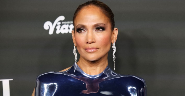 Jennifer Lopez mit strengen, gegelten Haaren und großen Diamantohrringen. Dazu ein metallenes Oberteil.