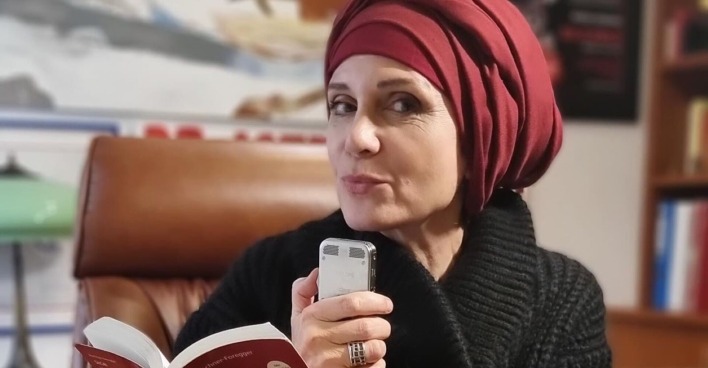 Astrid Wagner, mit Kopftuch, posiert sitzend mit Strafgesetzbuch