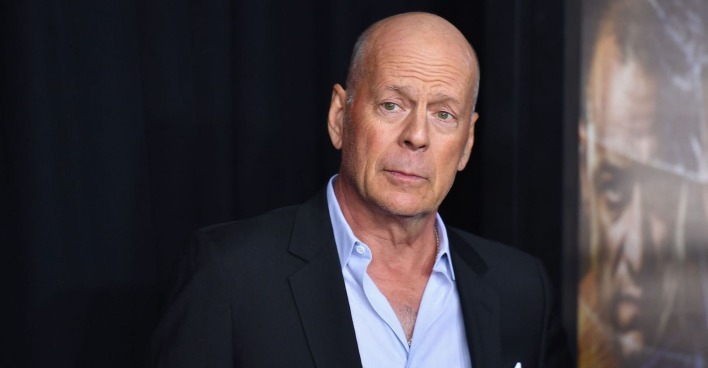Bruce Willis mit einem dunkelblauen Sakko und einem hellblauen Hemd.