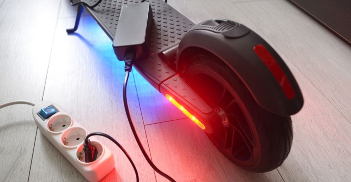 Ein E-Scooter wird an einer Steckdose aufgeladen.
