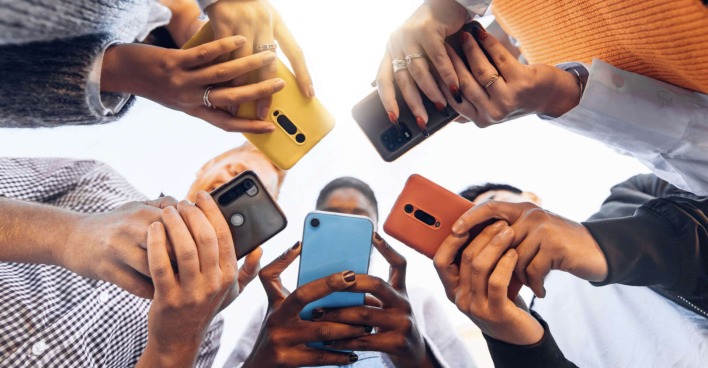 Jugendliche halten ihr Handy in der Hand.