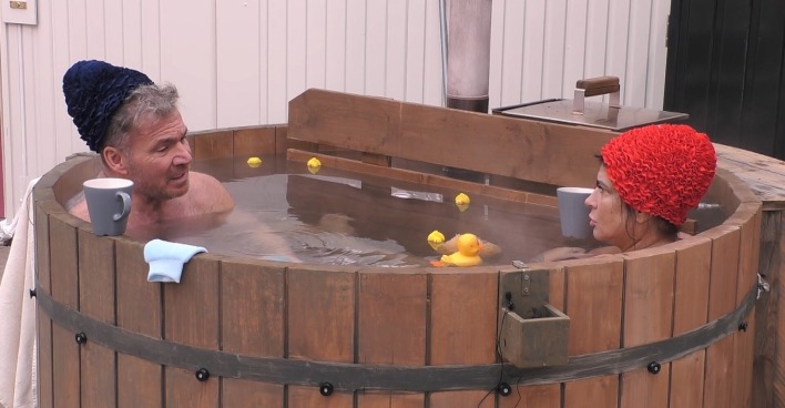 Peter Klein trägt eine schwarze Badehaube. Iris Klein eine rote Badehaube. Beide sitzen ins in einem warmen Whirlpool.