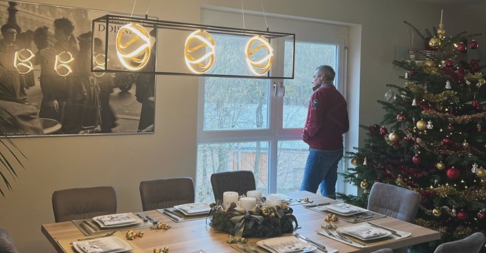 Karl Nehammer vor einem festlich gedeckte Tisch und dem Weihnachtsbaum. Er schaut aus dem Fenster.