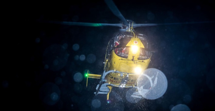 Ein gelber Rettungshubschrauber im nächtlichen Einsatz.