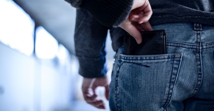 Eine Frau klaut eine Geldtasche aus der Hose eines Mannes.
