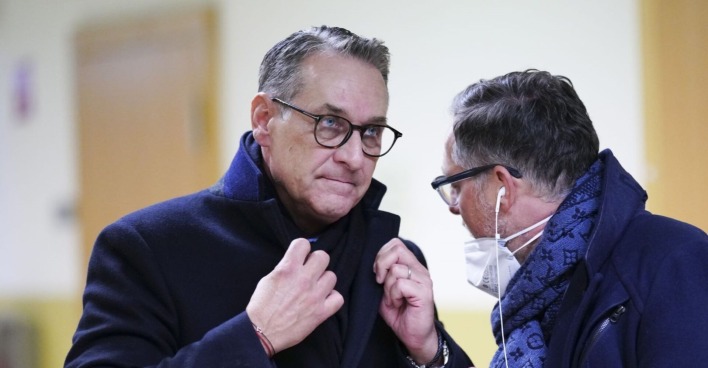HC Strache im Wintermantel richtet seinen Schal, im Gespräch, er hört zu.