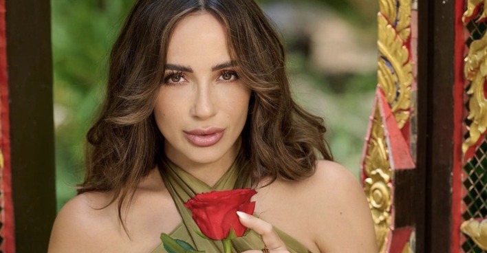 Jennifer Saro mit offenen braunen Haaren und einer Rose in der Hand.