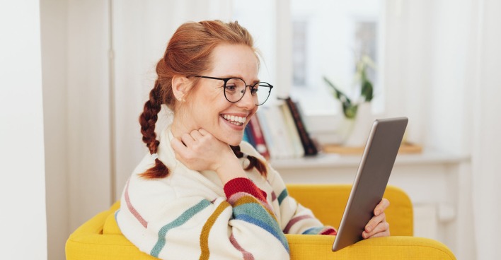 Frau sitzt lächelnd im Sessel | Credit: iStock.com/stockfour