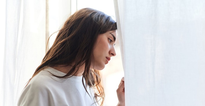 Frau steht am Fenster und grübelt | Credit: iStock.com/Javi Sanz