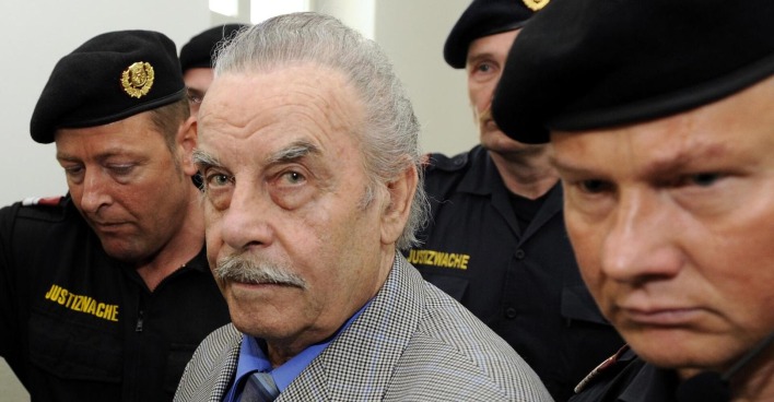 Josef Fritzl zwischen Polizisten am Weg ins Gericht. Er sieht direkt in die Kamera