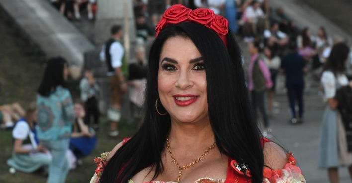 Iris Klein mit einem roten Haarreifen aus Rosen und offenen schwarzen Haaren.