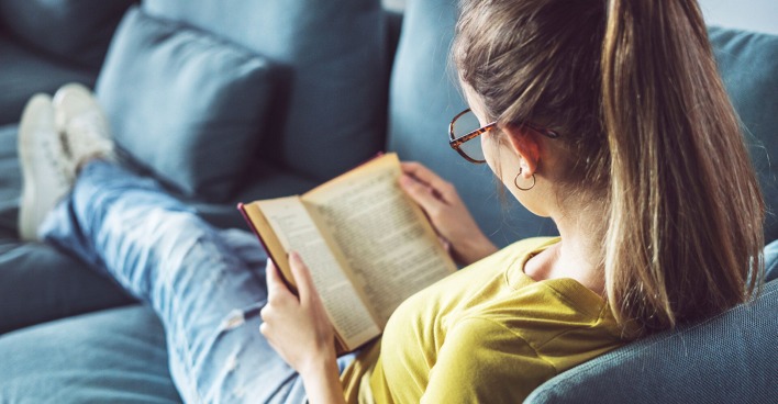 Frau liest ein Buch am Sofa | Credit: iStock.com/seb_ra