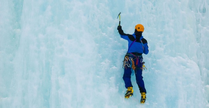 Ein Alpinist klettert einen vereisten Wasserfall hoch.