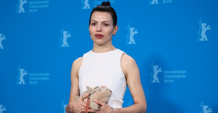 Anja Plaschg bei der Berlinale mit einem Stoffschwein in der Hand und einem weißen Kleid.