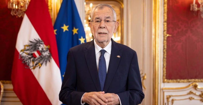 Alexander Van der Bellen hält eine Ansprache in der Präsidentschaftskanzlei der Hofburg, hinter ihm die österreichische und europäische Flagge.