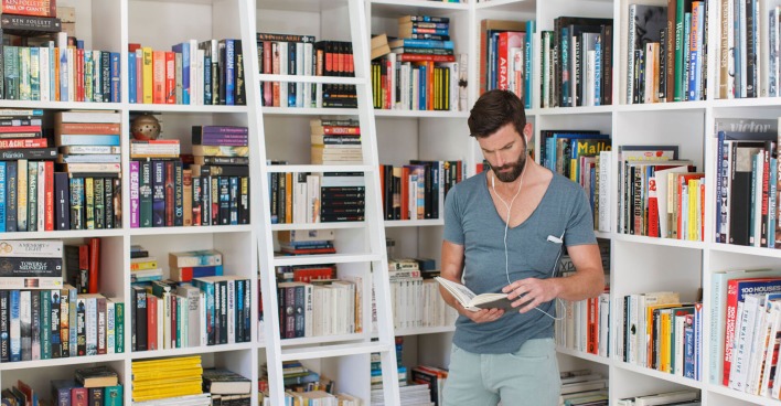 Mann steht bei seinen Bücherregalen | Credit: iStock.com/Astronaut Images