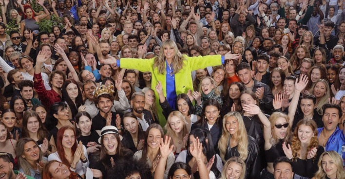 Heidi Klum mit einer gelben Jacke inmitten von Teilnehmern für Germanys Next Top Model 2024 bei einem Casting.