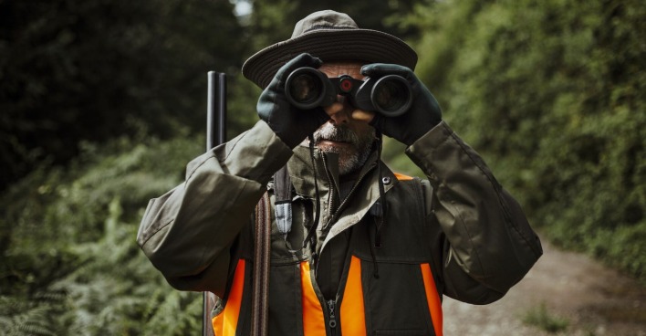 Ein Jäger mit Fernglas-Gucker unterwegs im Wald.
