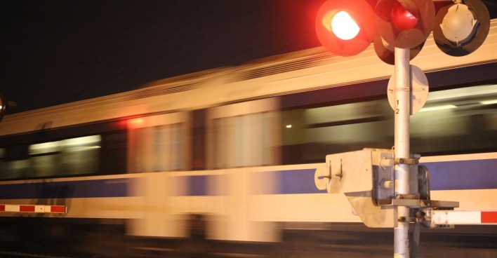 Mit Lichtzeichen geregelter Bahnübergang: Ein Zug braust vorbei.
